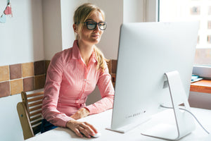 Woman with glasses looking at a computer screen