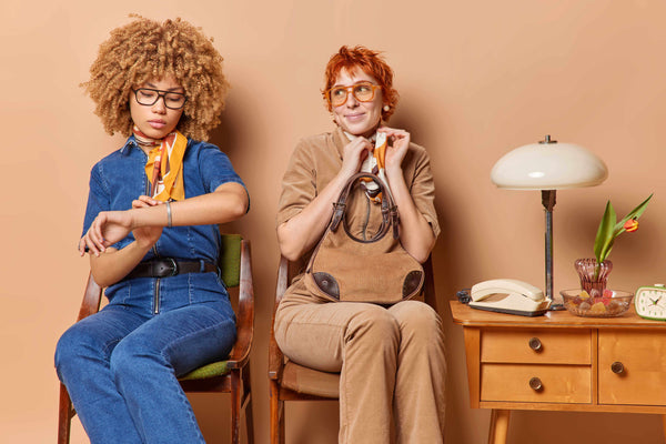 two women in retro 70s oufit and glasses sitting