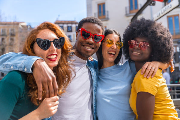 Multi-ethnic friend group smiling wearing fun, colorful sunglasses