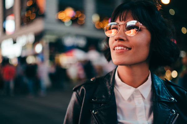 Woman wearing big glasses on a crowded street at night